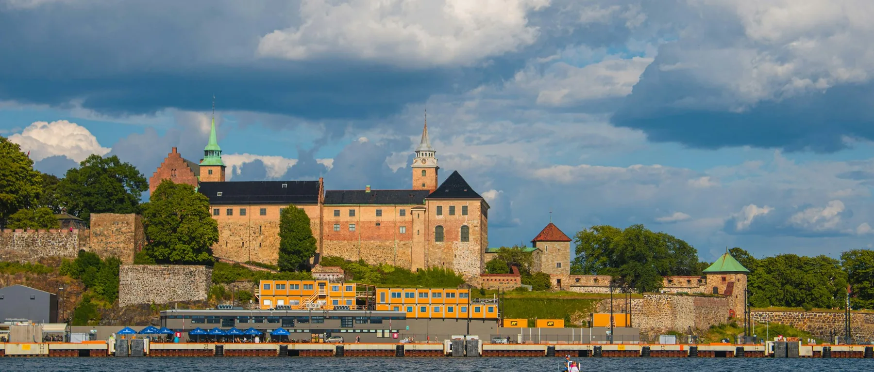 Akershus Fortress on its hill above the harbour under a broken, cloudy sky